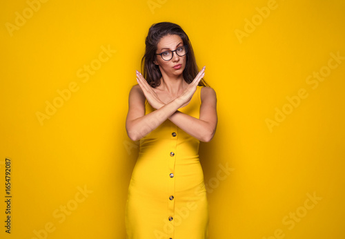 Limit. Woman gesturing stop or x sign with her arms, refuses or reject something, girl crossing her hands, isolated on yellow background.
