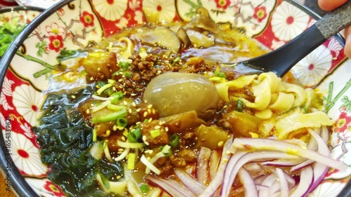 Spoon scooping spicy ramen noodles in bowl
