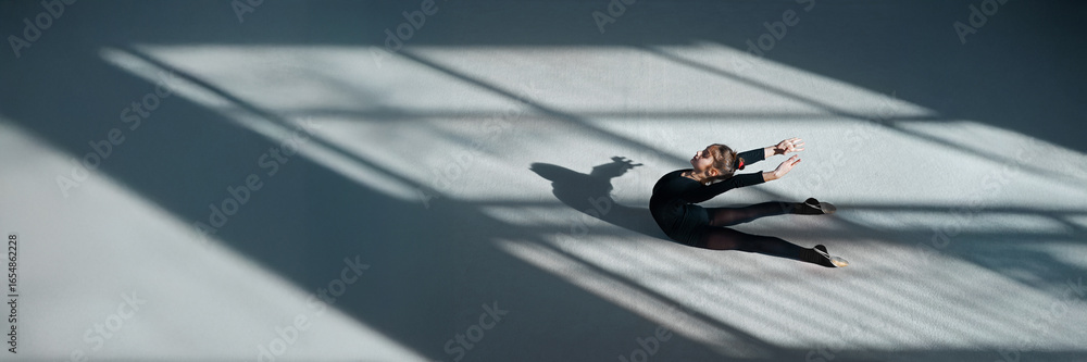Fototapeta premium Dancer on Studio Floor with Shadows, Wide Banner