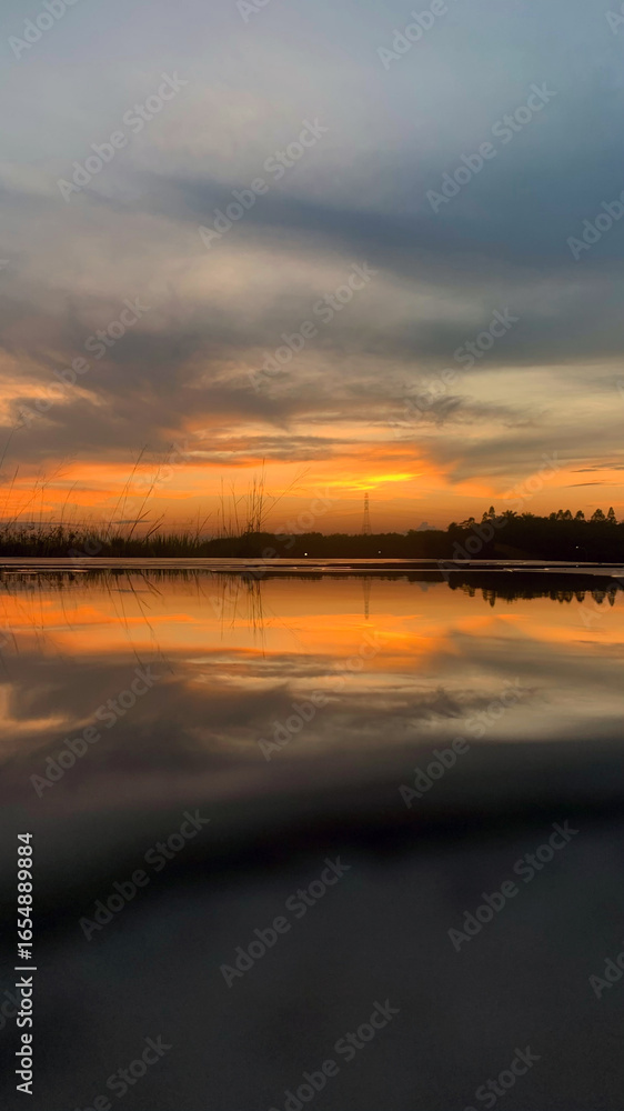 Fototapeta premium A serene sunset over calm water with golden and orange hues