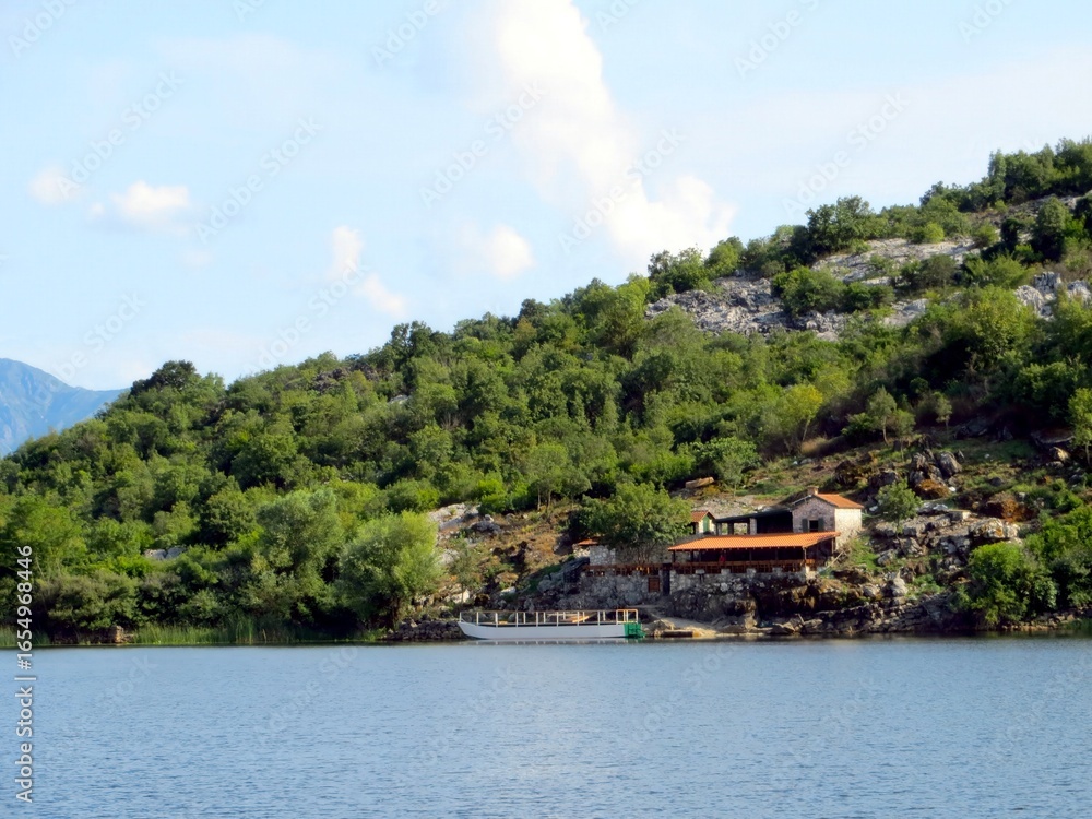 Fototapeta premium Charming Restaurant by the Tranquil Waters of Skadar Lake in Montenegro During a Sunny Afternoon