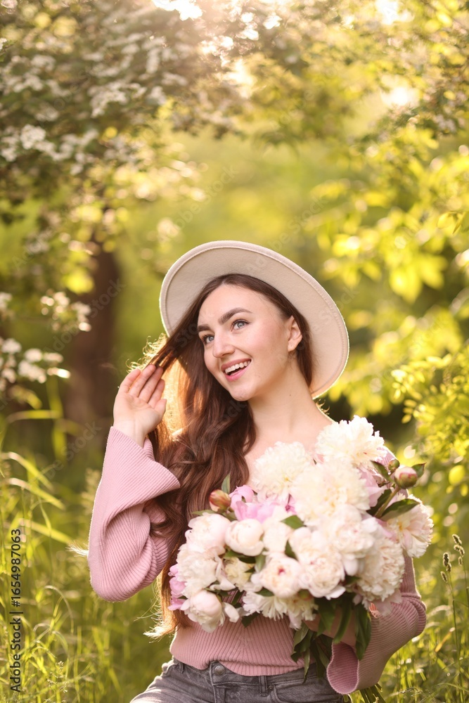 Fototapeta premium Beautiful woman with bouquet of peonies in park