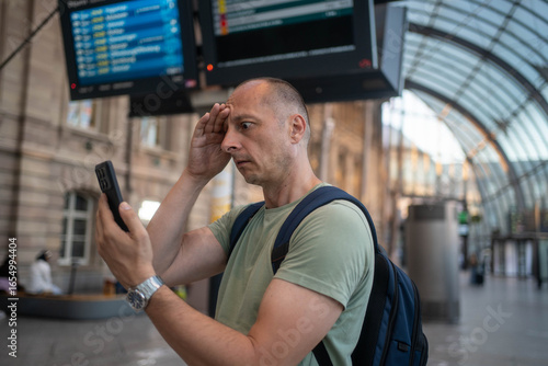 Obraz na plátně Worried man checking time while waiting for delayed public transport, frustrated
