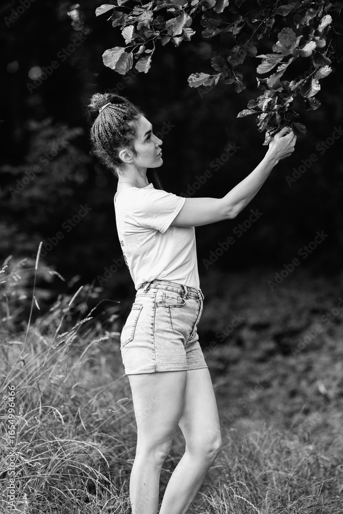 Portrait of a young beautiful girl in a T-shirt and shorts in a summer forest. Black and white photo. Portrait of a young beautiful girl in a T-shirt and shorts in a summer forest. Black and white photo.