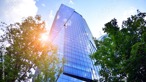Sustainable glass office building with trees for reducing carbon dioxide. Eco-friendly building in modern city. Office with green environment. Corporate building reduce CO2.