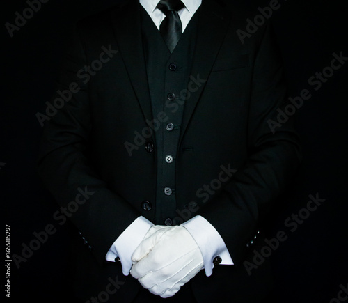 Formal Butler or Hotel Concierge in Dark Suit and White Gloves Standing at Attention. At Your Service.