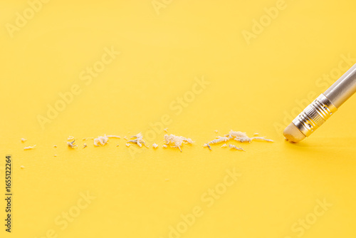 Pencil eraser working on yellow paper background. Mistake, erasing or correction concept. Copy space