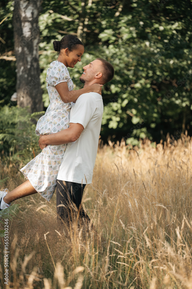 Fototapeta premium Romantic diverse couple embracing in nature, enjoying summer together, lifestyle and love concept, authentic outdoor moment.