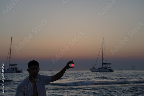Fotografi Puesta de sol sobre el mar con tonos intensos de rojo y púrpura, sol descendiend