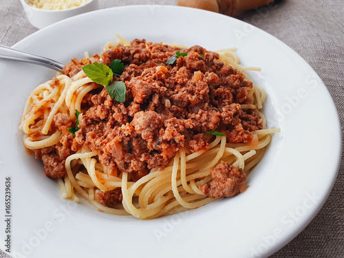 spaghetti bolognese with basil on a white plate