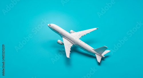 White airplane model on turquoise background, showcasing travel and journey concept. Ample free space for text or logo placement.