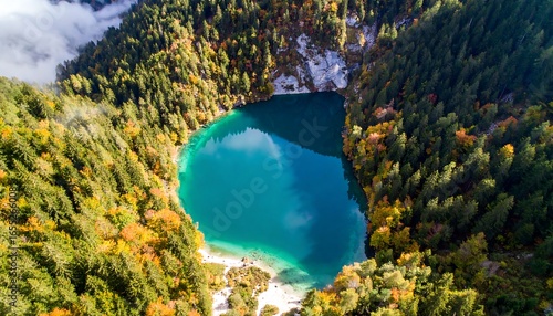 High-angle view of a turquoise lake nestled within a valley surrounded by colorful autumn foliage.