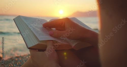 Person reading a book on a pebbled beach during summer sunset in Croatia