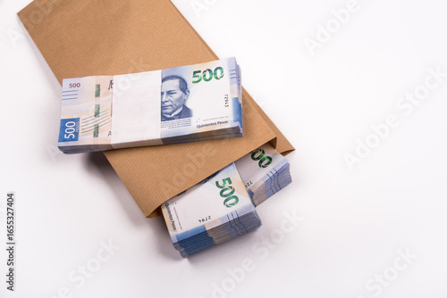 Bolsa de papel llena de billestes mexicanos de 500 pesos, referente a ahorros, soborno o fraude, sobre fondo blanco