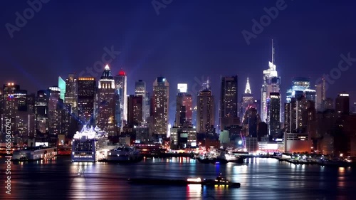 Wallpaper Mural Manhattan, New York City. A nighttime cityscape photograph showcasing a city skyline with skyscrapers illuminated in various shades of blue and white. The cityscape is set against a dark sky. Torontodigital.ca