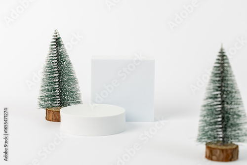 A white box is placed in front of two green pine trees