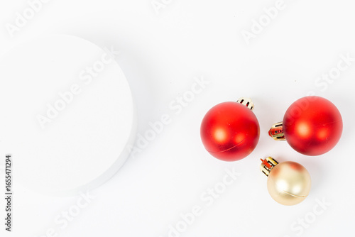 Three red and gold ornaments are on a white background