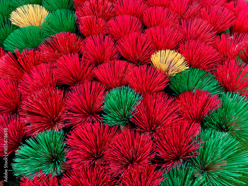Series of religious incense stick arranged beautifully into shapes of flowers and floral decoration. In red, green, and yellow color. Creativity of art installation made of sticks. Seamless background