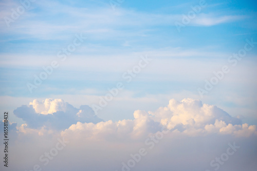 Fluffy cumulus clouds rise majestically along the horizon sky
