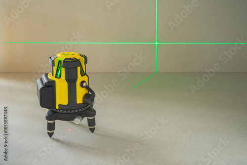 Yellow laser level machine equipment with the green laser lines shown cross lines on floor and wall