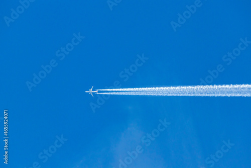 Airplane flying with contrail in blue sky