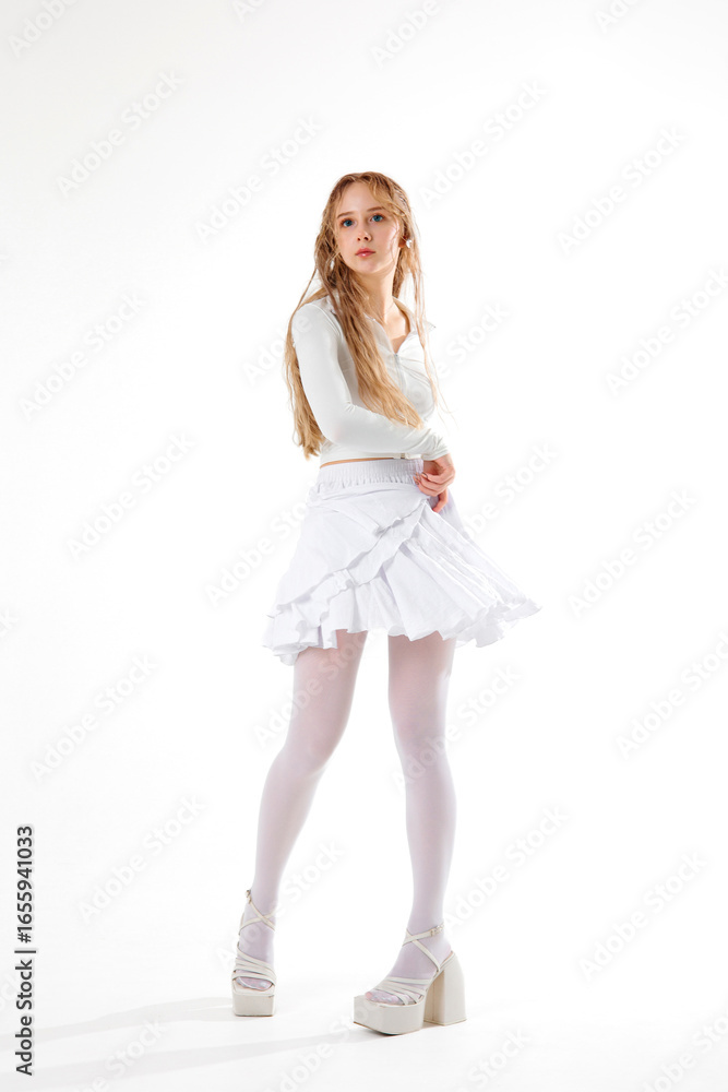 Model poses in a stylish white outfit with heels in a bright studio setting Model poses in a stylish white outfit with heels in a bright studio setting