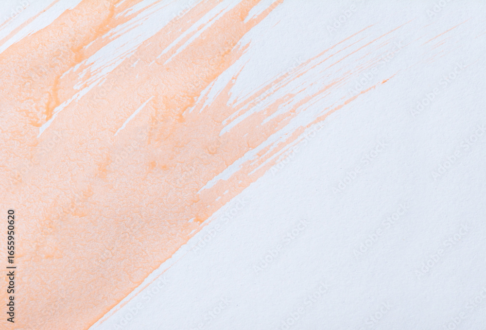 Fototapeta premium Light orange watercolor wash and splatters on textured white paper. Paint forms several elongated fluid streaks that run diagonally across. Small isolated splatters and drips are scattered