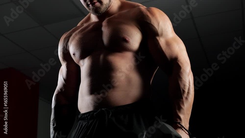 A physically fit individual engaged, working their biceps with a dumbbell. A well-defined physique with a six-pack, perfectly sculpted abs, triceps, chest, and shoulders, against a dark background. 