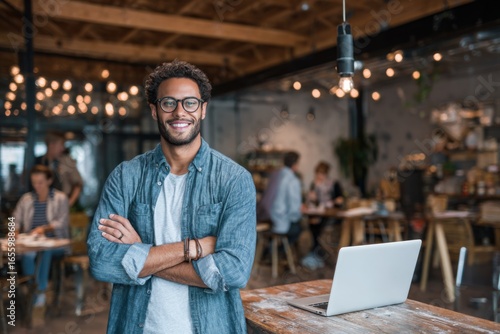 Confident man smiling in modern cafe with laptop and warm ambiance