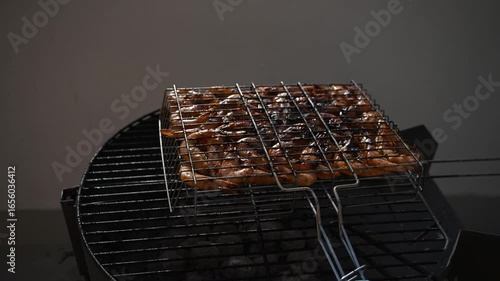 Sizzling shrimps  grilling over hot charcoal, professional chef carefully flipping shrimps  for even cooking and perfect golden-brown color during outdoor summer barbecue gathering
