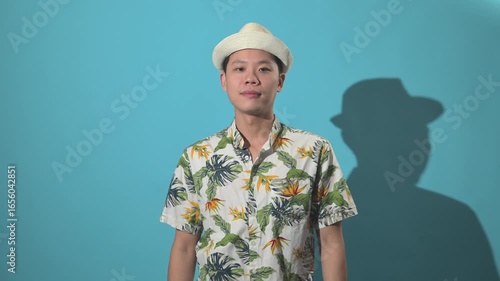An Asian person drinking from a coconut and making an inviting gesture, filmed against a simple background, symbolizing tropical refreshment, hospitality, lifestyle, and vacation vibes