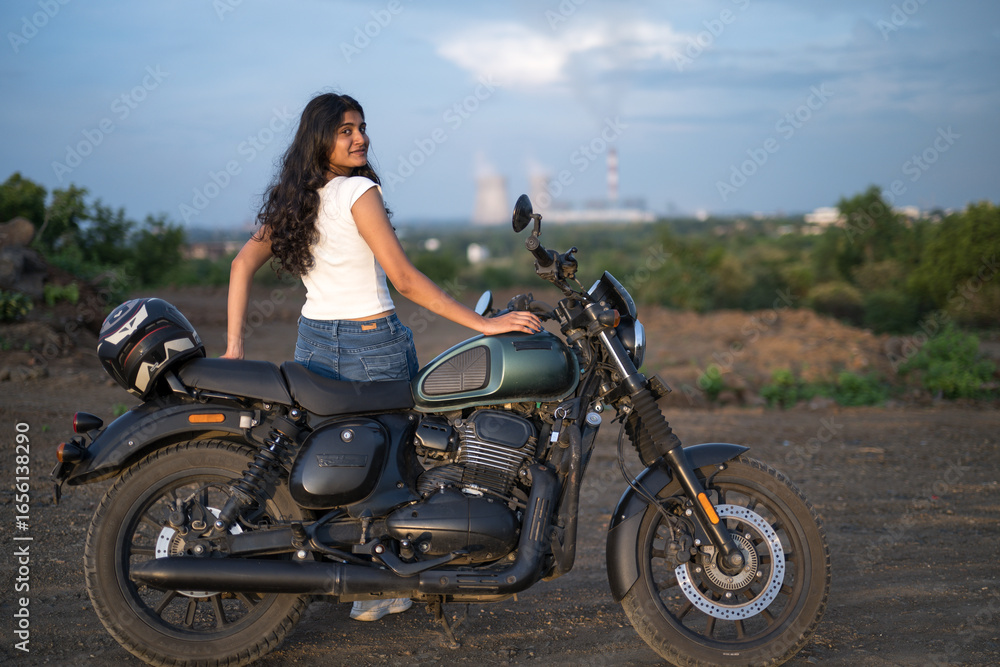Fototapeta premium Strong independent Indian woman biker: beautiful girl, stylish rider, motorcycle adventure, elegant jacket, confident posture, powerful machine, free spirit, road journey, fearless attitude.