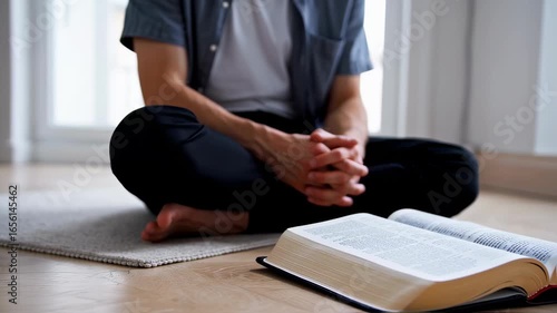 man sitting cross-legged on floor praying in front of a book – seamless loop

