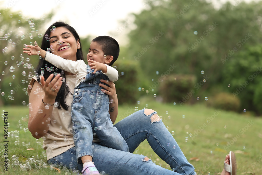 Fototapeta premium Mother And Child Enjoy Playing With Bubbles Outdoors