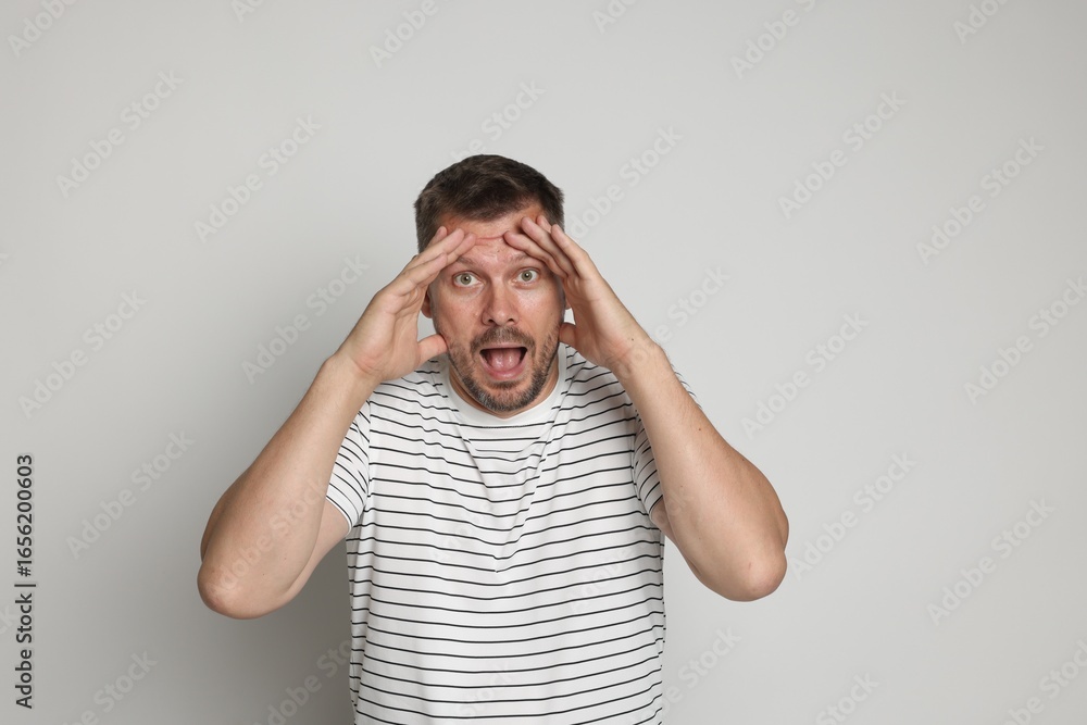 Naklejka premium Man suffering from panic attack on light grey background