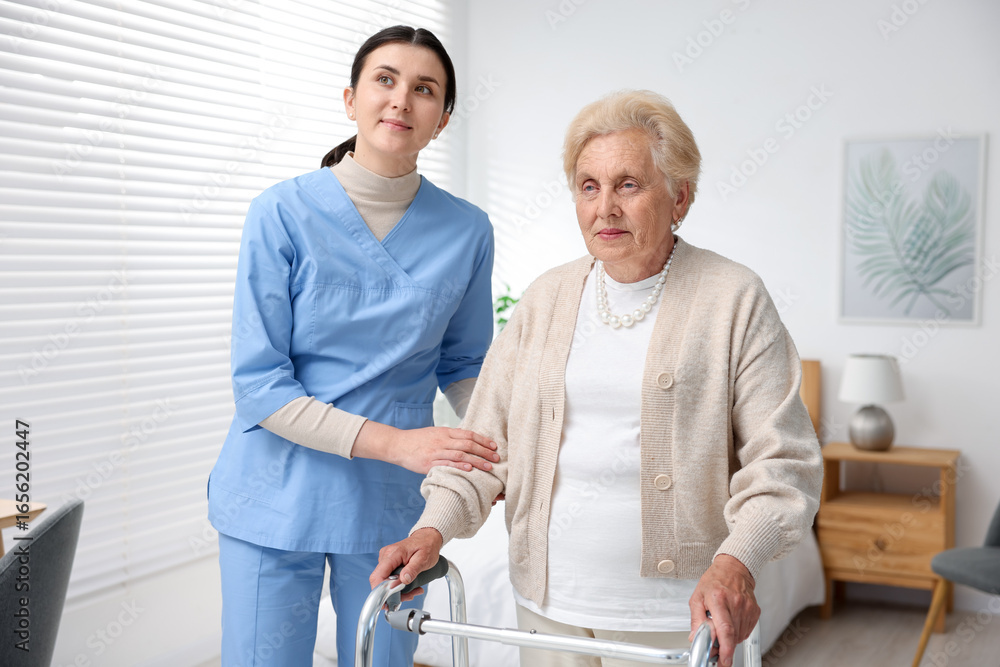 Obraz premium Nurse assisting senior woman with walking frame indoors. Home health care service