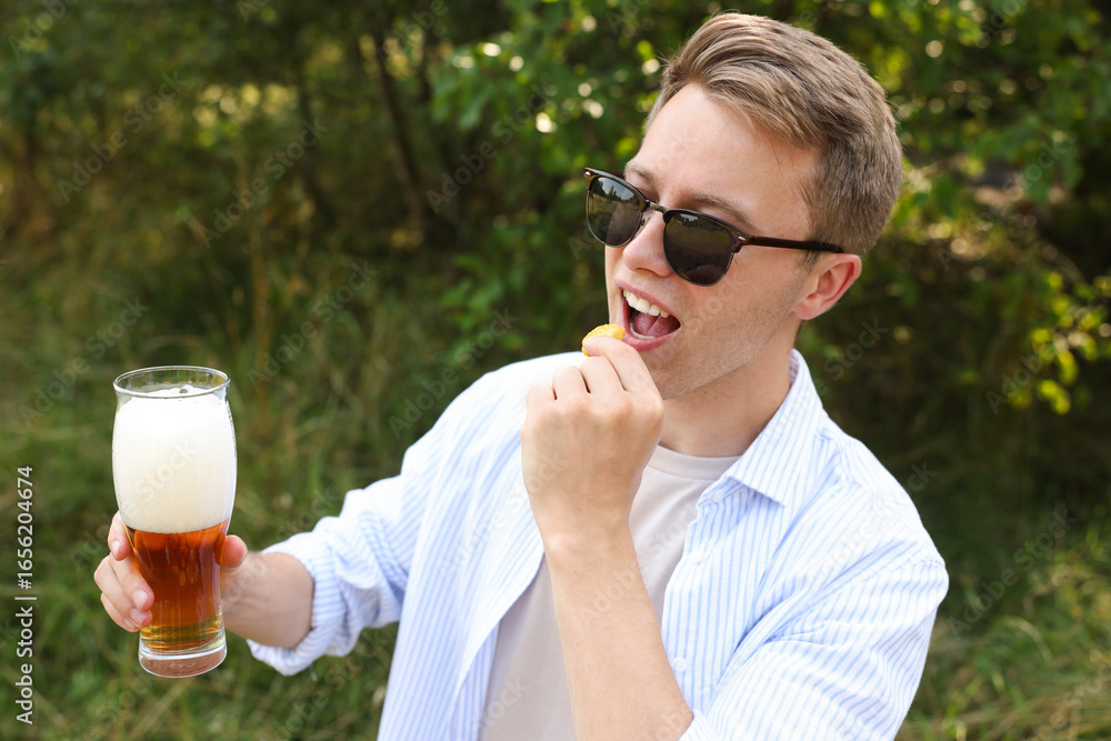 Fototapeta premium Handsome young man with glass of beer outdoors