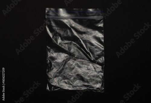 Transparent empty ziplock bag isolated on black background, clear plastic pouch with resealable closure for storage, packaging, organizing, food, travel, and household use.