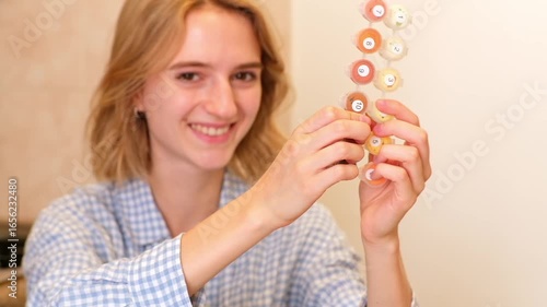 A happy young woman with a joyful smile holds up a set of numbered paints, expressing the fun and creative satisfaction of a paint-by-numbers art hobby.