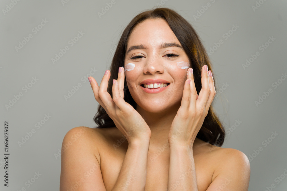Young woman applying moisturizer cream for skincare routine Young woman applying moisturizer cream for skincare routine