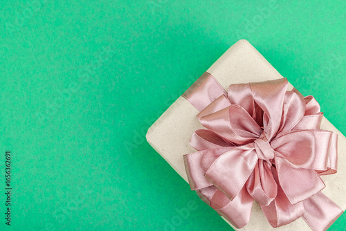Eco-friendly gift boxes wrapped in kraft paper and decorated with satin ribbons on green background