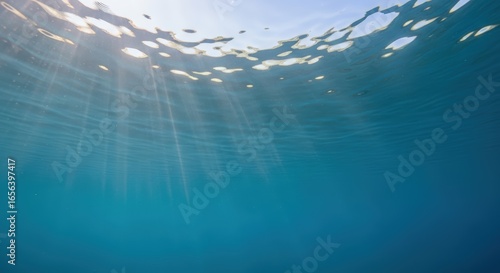 underwater sun rays breaking through water surface in blue ocean