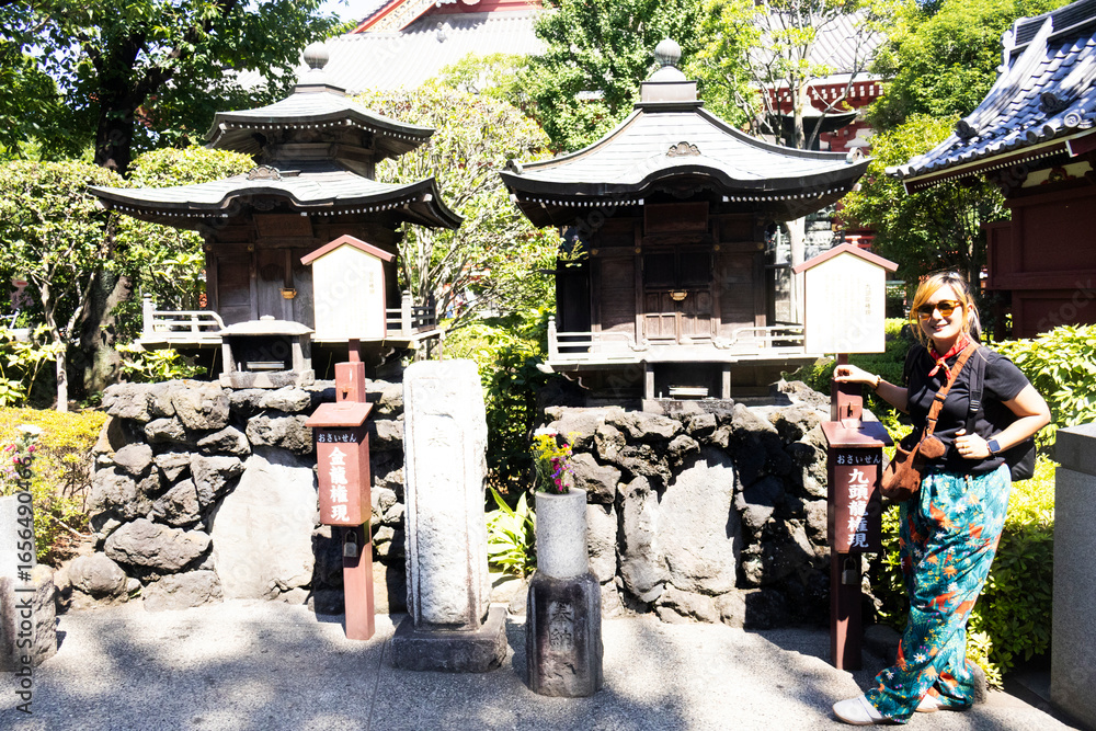 Obraz premium Travelers thai women people travel visit take photo with holy small antique shrine in garden park and respect praying god deity angel of Sensoji temple at Asakusa city on July 21, 2025 in Tokyo, Japan
