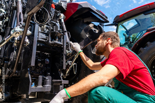 Agricultural machinery mechanic checking farm tractor