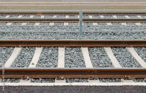 Pattern of railway tracks on gravel as a side view. Rails lead to Helsinki. Steel construction of railroad tracks. Cloudy summer day in Finland. 