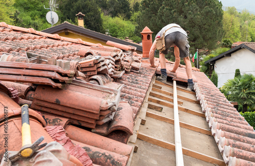 Roofer inspecting and repairing roof on a sunny day, house maintenance work.