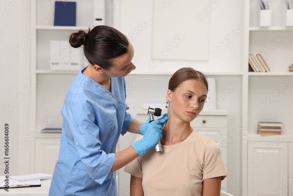 Fototapeta premium Doctor examining young woman's mole with dermatoscope in hospital