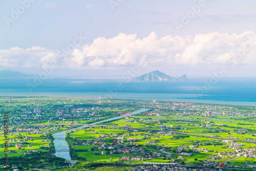 Dusk panorama from Dongshan, Taiwan, featuring Lanyang Plain, Guishan Island, distant sea, and cloud-dotted blue sky.