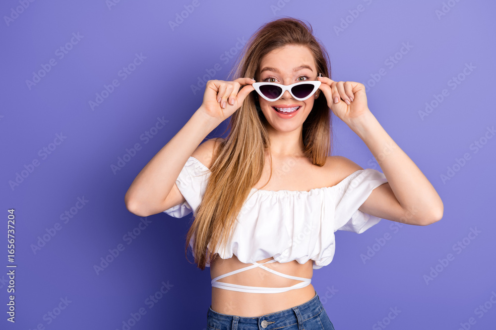 Fashionable young woman enjoying a cheerful day with a radiant smile in stylish summer clothing against a purple backdrop Fashionable young woman enjoying a cheerful day with a radiant smile in stylish summer clothing against a purple backdrop