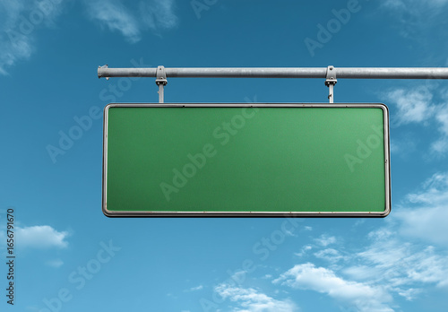 Empty green road sign hanging over blue sky with clouds